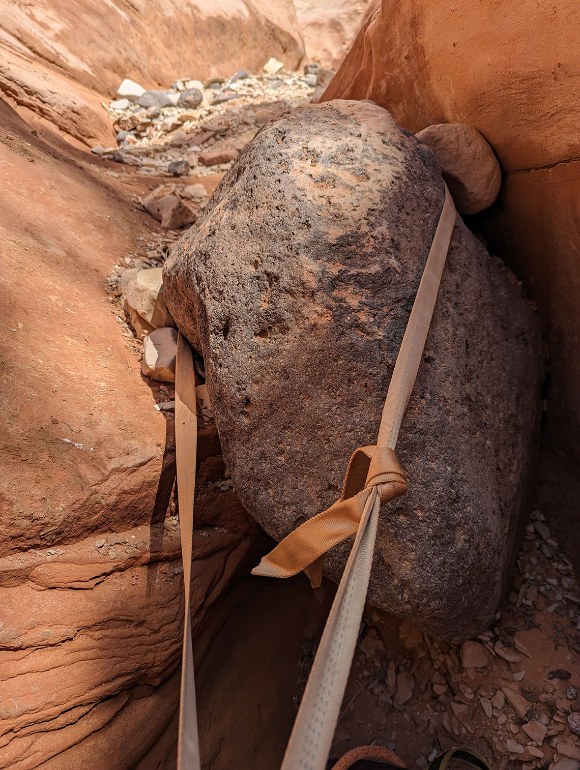 Tan webbing around a small boulder as the anchor for rap 2